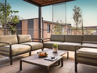 Nowoczesny balkon z wygodnymi meblami i widokiem na domy oraz błękitne niebo