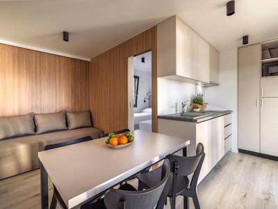 Mała nowoczesna kuchnia i jadalnia z drewnianą okładziną i szarymi krzesłami