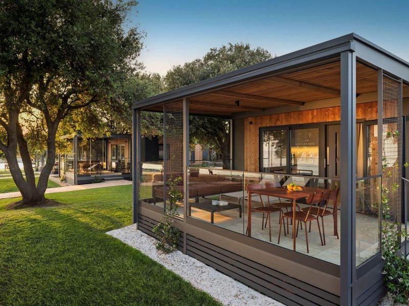 Nowoczesna szklana kabina z zadaszonym tarasem na zielonym terenie hotelu o zachodzie słońca.