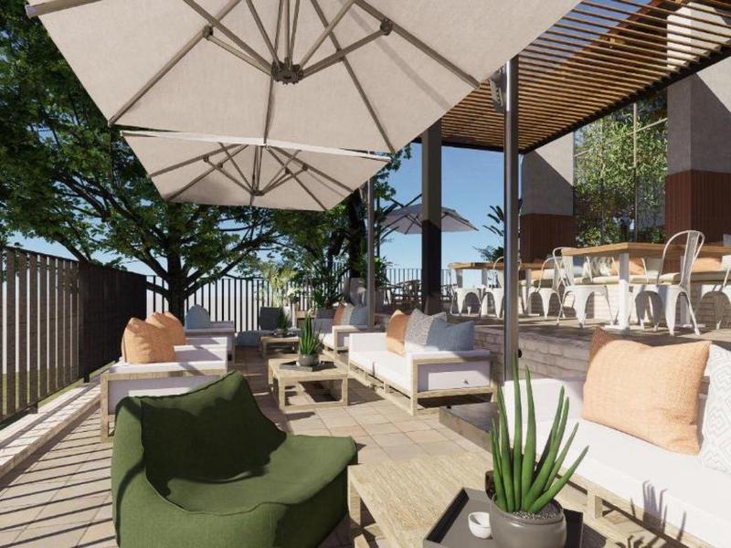 Nowoczesny taras z wygodnymi sofami, parasolem i roślinami w naturalnym otoczeniu.