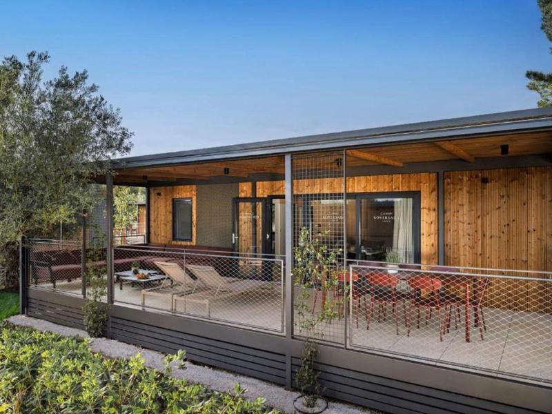 Nowoczesna drewniana chatka wakacyjna z werandą i meblami ogrodowymi pod czystym niebem