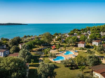 Ferienanlage mit kleinen Häusern, Pool und nah am blauen Meer unter klarem Himmel.