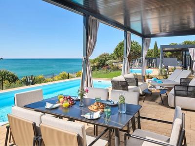 Nowoczesny teren zewnętrzny z basenem i stołem jadalnym z widokiem na morze.