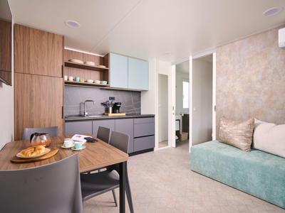 Nowoczesne mieszkanie z aneksem kuchennym, stołem i sofą w neutralnych kolorach