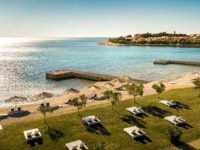 Widok na słoneczną plażę z leżakami i spokojnym morzem pod czystym niebem.