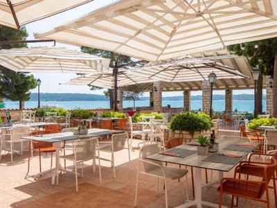 Open terrace with tables and chairs under umbrellas overlooking the sea.