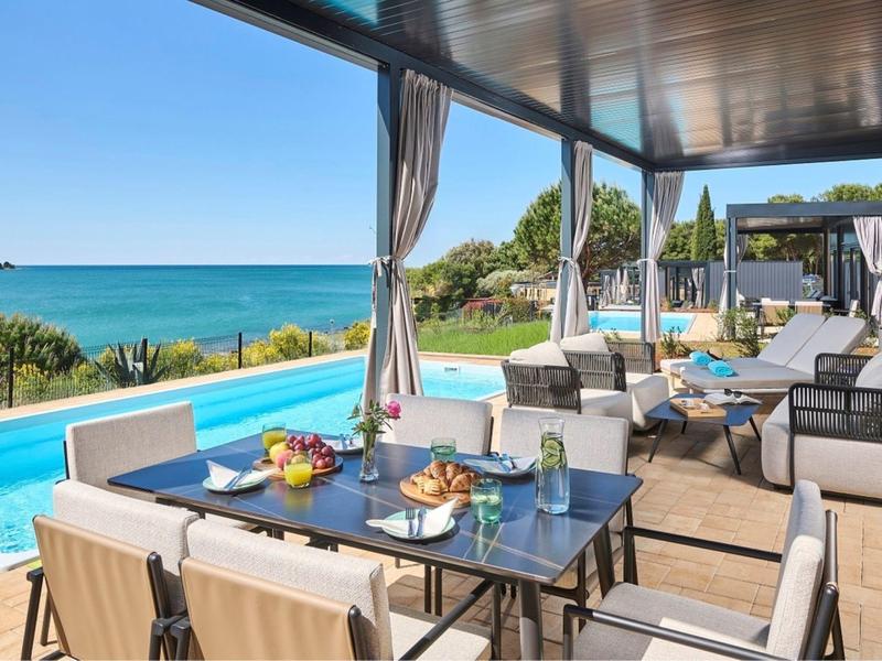 Nowoczesny teren zewnętrzny z basenem i stołem jadalnym z widokiem na morze.