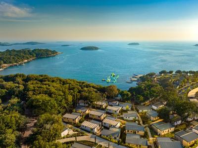 Blick auf ein Küstenresort mit Bungalows, umgeben von Wald und Blick auf das blaue Meer.