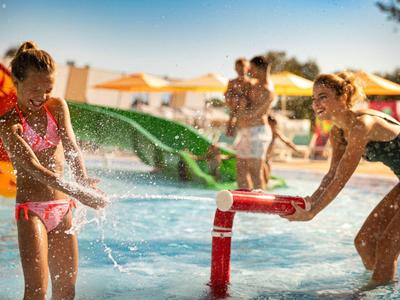 Dzieci bawią się na placu zabaw wodnym podczas słonecznego dnia wakacji.