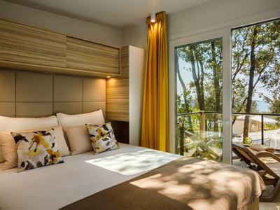 Jasna i przytulna sypialnia z łóżkiem podwójnym i balkonem z widokiem na ogród.