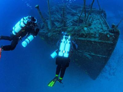 Dos buceadores exploran un naufragio hundido en agua clara.
