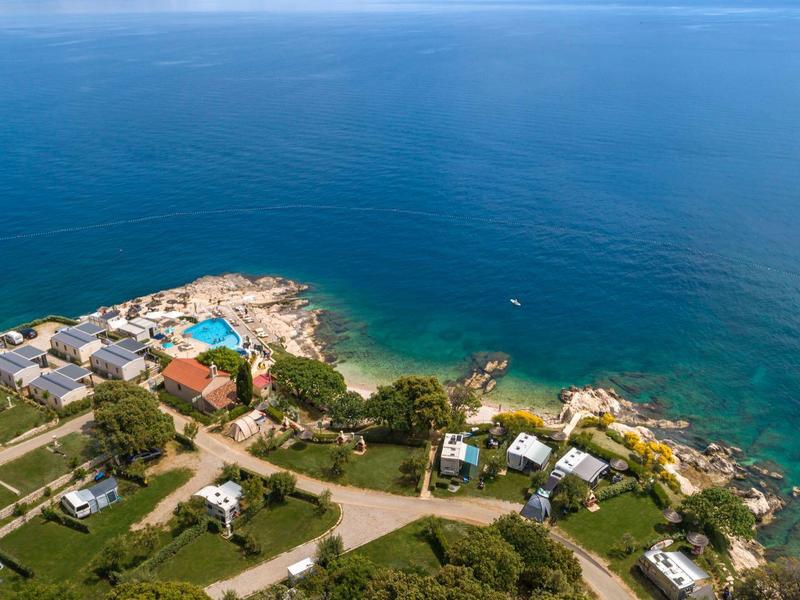 Costa con casas, calles y una piscina junto al mar azul.