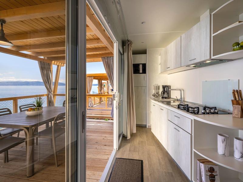 Cocina moderna con vistas a una terraza y al mar a la luz del día.