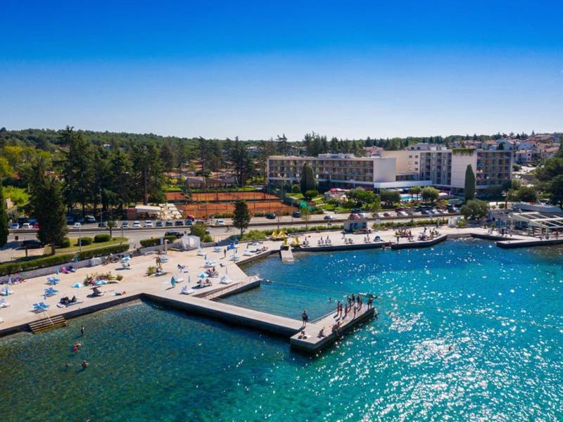 Puerto con agua azul, muelle y complejo hotelero adyacente bajo cielo despejado.