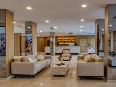 Moderner Hotel-Loungebereich mit beigen Sofas, Sesseln und hellem Marmorboden.