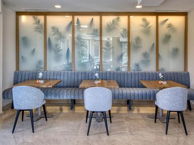 Moderner Hotel-Loungebereich mit gepolsterten Stühlen und Sofas vor mattierten Fenstern.