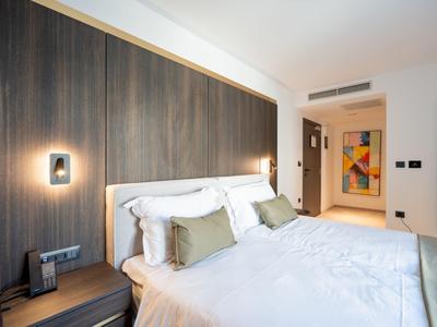 Modernes Hotelzimmer mit großem Bett, Holzwand und indirekter Beleuchtung.