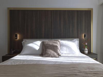 Modernes Hotelzimmer mit großem Bett, Holzpaneel und gedämpfter Beleuchtung.