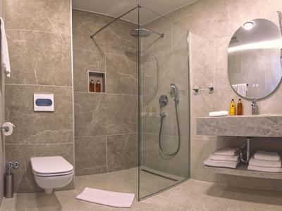 Modernes Badezimmer mit begehbarer Dusche, Toilette und Waschbecken in neutralen Farben.
