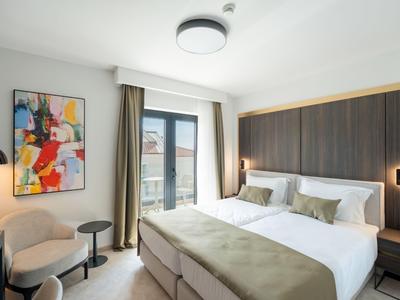 Modern eingerichtetes Hotelzimmer mit Doppelbett, Sitzbereich und großem Fenster.