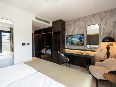 Moderner Hotelzimmer mit Schreibtisch, kleinem Sofa, Spiegel und begehbarem Kleiderschrank.