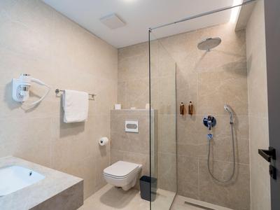 Modernes Badezimmer mit Glasdusche, weißem Waschbecken und Wandtoilette.