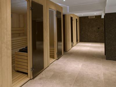 Modernes Saunabereich mit Holzwänden und Glasabtrennungen in einem Hotel.