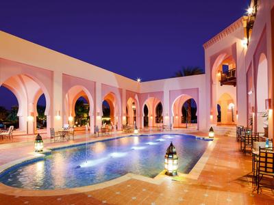 Piscine d'hôtel éclairée avec arches arabes la nuit