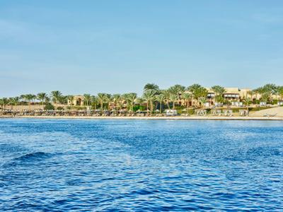 Vista di un resort sulla spiaggia con cielo azzurro terso e mare calmo.
