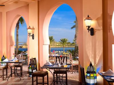 Terrazza unica con archi orientali che si affaccia su palme e acqua blu.