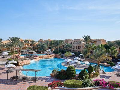 Groot zwembad met parasols en palmbomen in een zonnig resort.