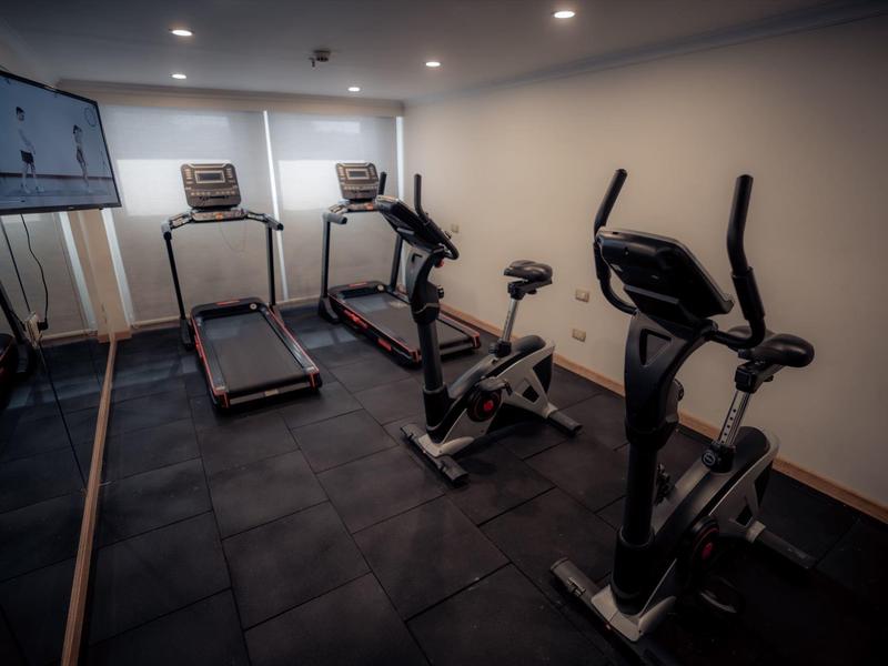 Salle de sport avec tapis de course et vélos stationnaires.