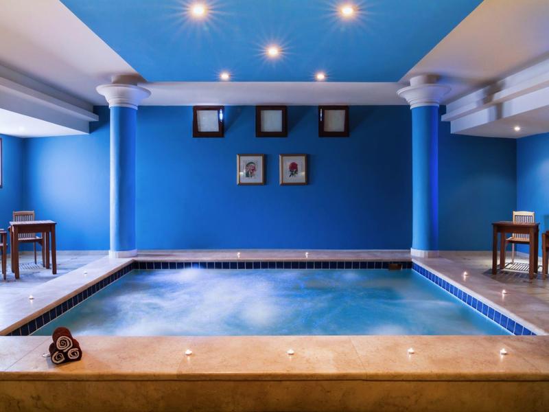 Piscine intérieure avec des colonnes blanches et des murs bleus lumineux.