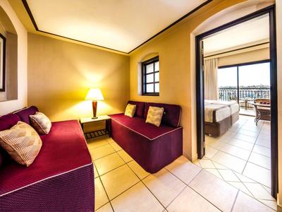 Bright hotel room with cozy sofas and adjoining bedroom with terrace.