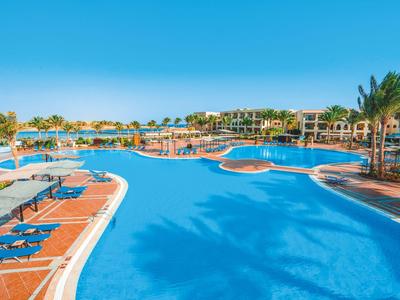 Großer Außenpool mit Liegestühlen und Palmen in einem sonnigen Hotelresort