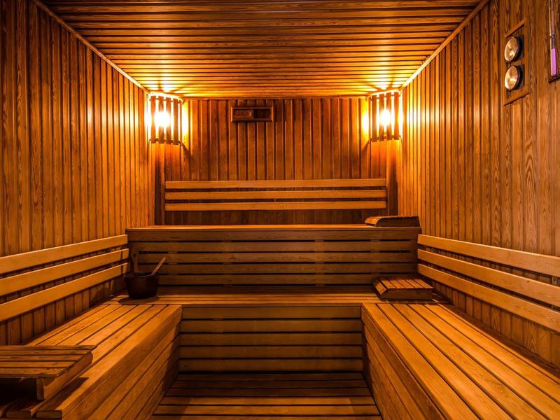 Interno di una sauna in legno con panche e illuminazione calda.