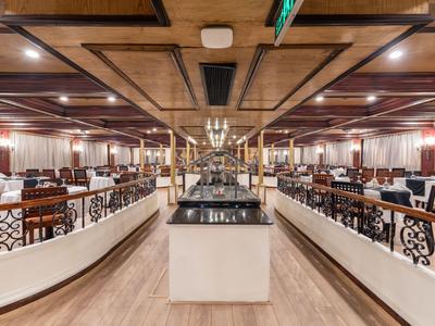 Large dining hall with wooden floor and elegant furniture under warm lighting.