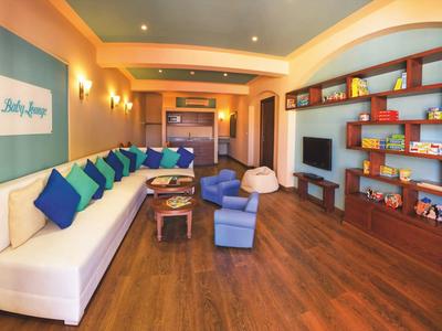 Sala de estar moderna con sofá blanco, cojines coloridos y estanterías de madera llenas de juegos de mesa.