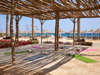 Espace extérieur convivial avec tapis de yoga sous une pergola en bois naturel sur la plage.