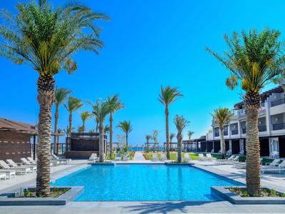 Modern hotelzwembad met palmbomen en heldere blauwe lucht bij zonnig weer