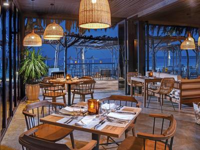 Restaurante elegante con muebles de madera y vista a la terraza al anochecer.