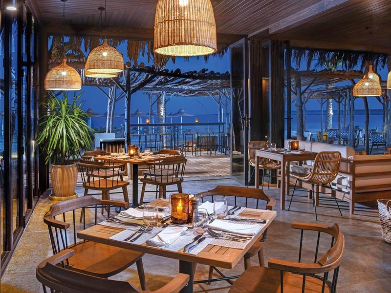 Restaurante elegante con muebles de madera y vista a la terraza al anochecer.