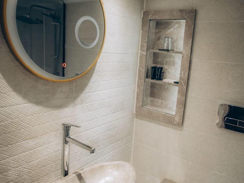 Bagno moderno con specchio rotondo, lavabo ovale e wc bianco.