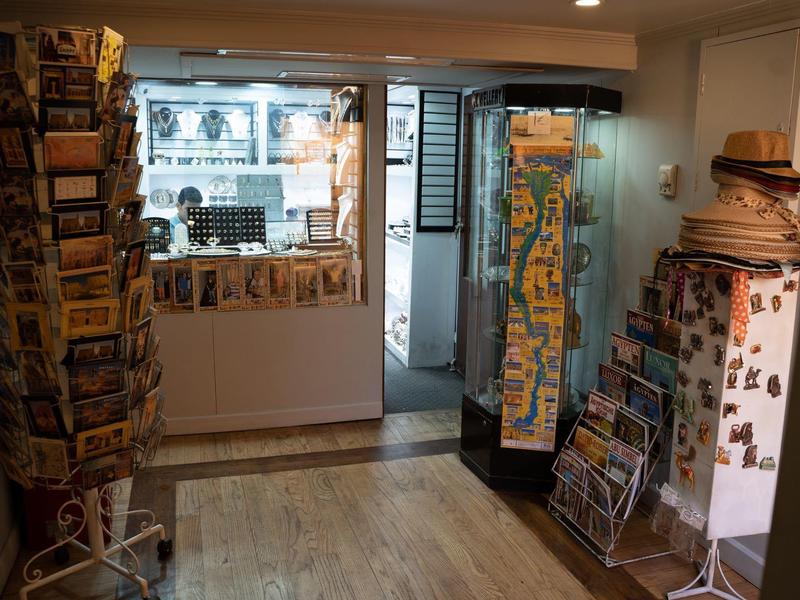 Tienda de recuerdos con expositores de postales y mostrador en una habitación pequeña y luminosa