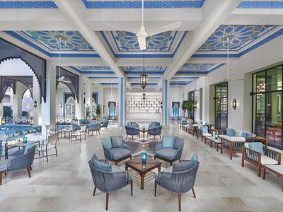 Eleganter Hotel-Lobbybereich mit blauen Sesseln und kunstvoll dekoriertem Deckenmuster.