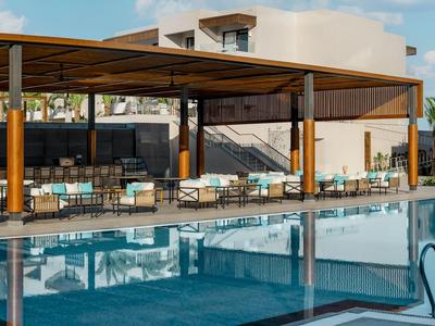 Moderní lounge u bazénu s krytým posezením a velkým čistým bazénem v resortu.