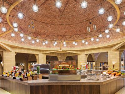 Buffet opstelling onder een warme, ronde kroonluchter in een ruime hotel eetzaal.