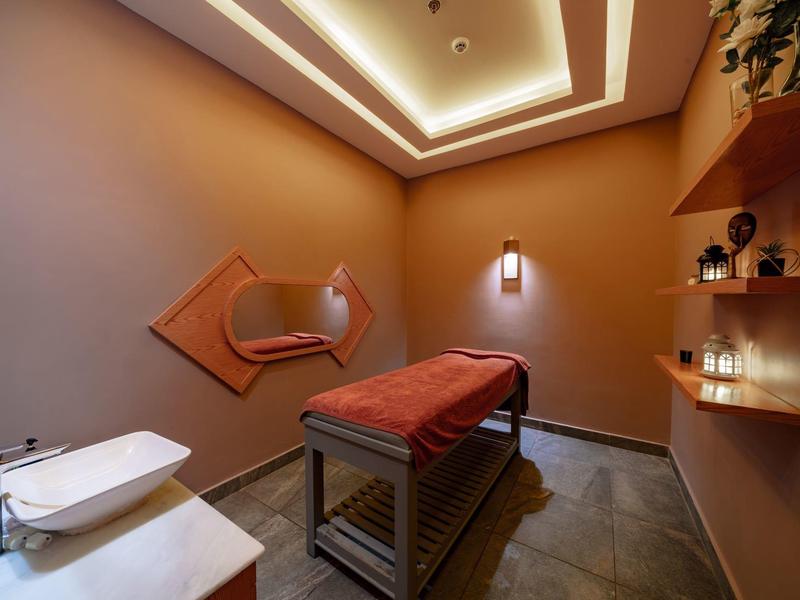 Einzelner Massagetisch in warm beleuchtetem, minimalistischem Raum mit Regalen und Handtüchern.