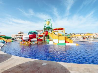 Parque acuático colorido con toboganes y piscina bajo cielo azul.
