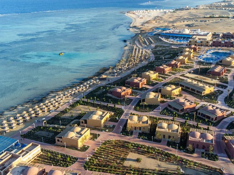 Vista aérea de una ciudad costera con hoteles, playas y agua turquesa clara.